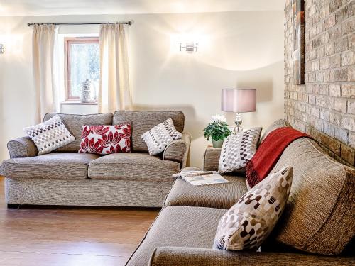 un salon avec un canapé et un mur de briques dans l'établissement Brook House Farm Cottage, à Scamblesby