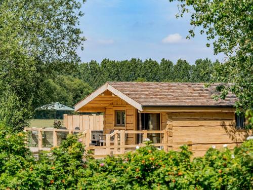 a wooden cabin with a fence and trees at Kingfisher Cabin in Croft