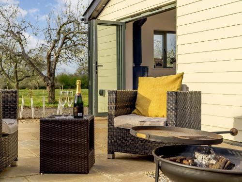 a patio with a fire pit and a chair and a table at Bramley Cottage in North Weald
