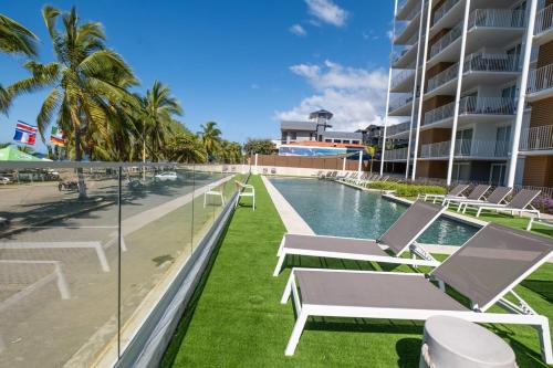 Una piscina con tumbonas junto a un edificio. en Stylish 1-BR Oceanfront Condo with Panoramic Views, en Jacó