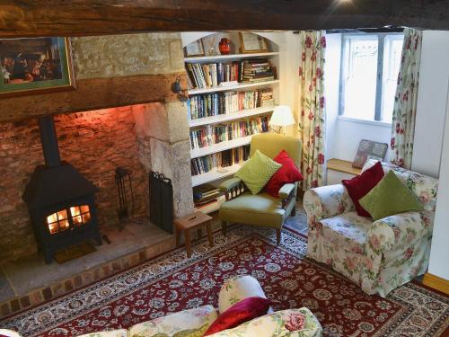 a living room with a fireplace and a book shelf at Rose Cottage in Cold Ashton
