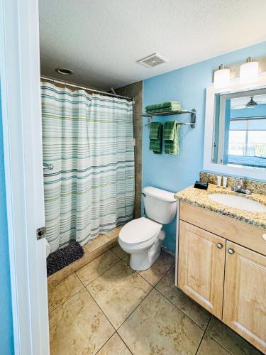 a bathroom with a toilet and a sink and a mirror at Shore Thing in St. Pete Beach