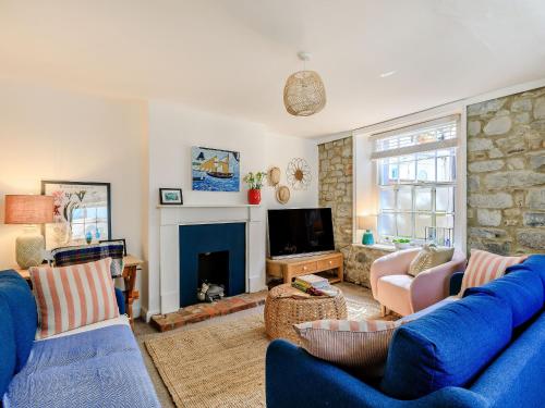 a living room with blue couches and a fireplace at Samphire Cottage in Lyme Regis