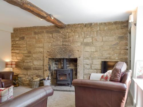 ein Wohnzimmer mit einer Steinmauer und einem Kamin in der Unterkunft Blackcurrant Cottage At Stanton Ford Farm in Baslow