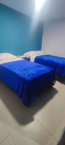 two beds with blue sheets in a room at Hotel los Lanceros 