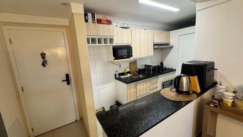 a small kitchen with a black counter top at Quarto em Ap no Renascença in São Luís