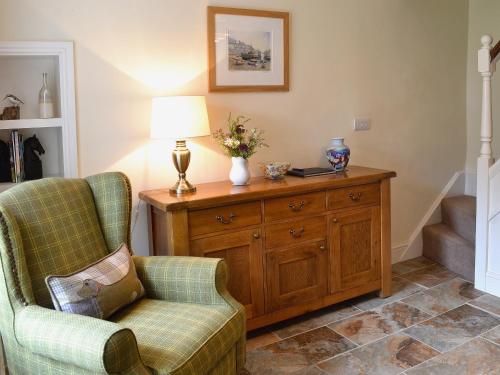 a living room with two chairs and a wooden dresser at Sunloch Cottage in St Just