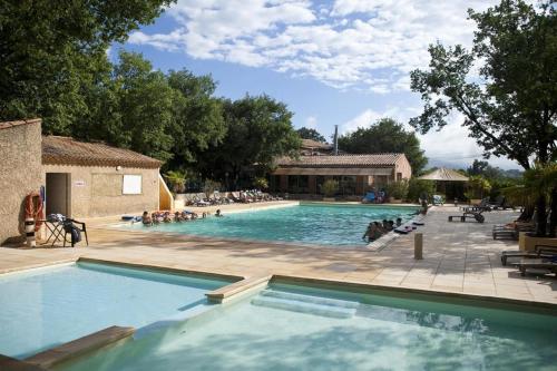 uma grande piscina com pessoas sentadas à sua volta em Domaine Les Chênes Blancs em Saint-Saturnin-dʼApt