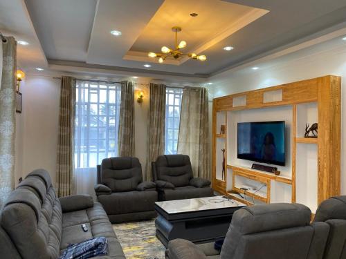 NyahururuにあるEmet Country Farm Homeのソファと椅子とテレビのあるリビングルーム
