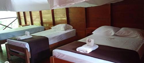a room with three beds with towels on them at Tambopata Edosikiana Ecolodge in Tambopata