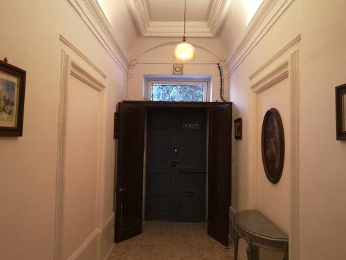 a hallway with a black door and a window at 17 Domus Mariae Town House in Senglea