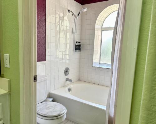 a bathroom with a white tub and a toilet and a window at Peach Blossom Country House in Hemet