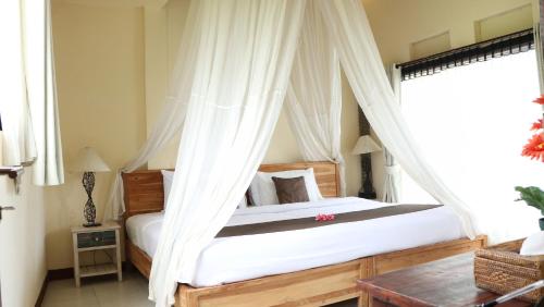 a bedroom with a canopy bed with white drapes at Villa JJ and Spa Ubud in Ubud