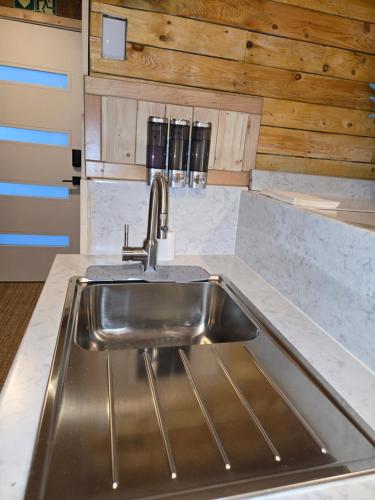 a stainless steel sink in a kitchen with wooden walls at Rustic Guest Suite in Ucluelet