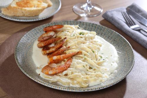 a plate of pasta with shrimp and bread on a table at Holiday Inn Navojoa by IHG in Navojoa