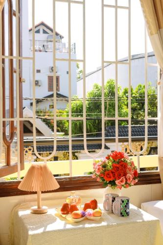 a table with a plate of food and a vase of flowers at Hotel Ngọc My in Phan Thiet