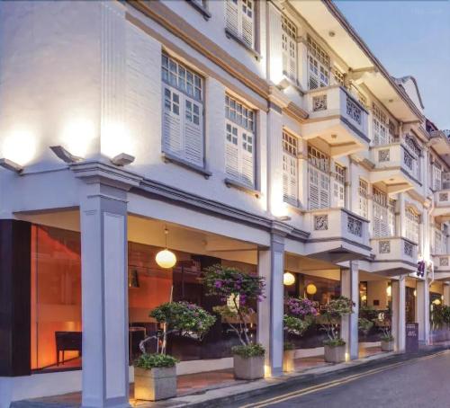 a white building with windows and potted plants on a street at A Hotel Chinatown- Stay From 8PM To 9AM in Singapore