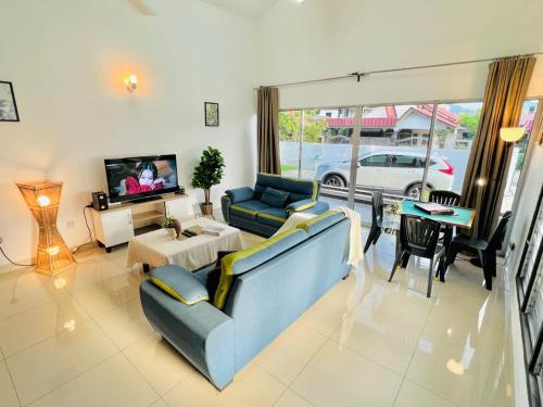 a living room with a blue couch and a tv at Laksamana Homestay in Batu Pahat