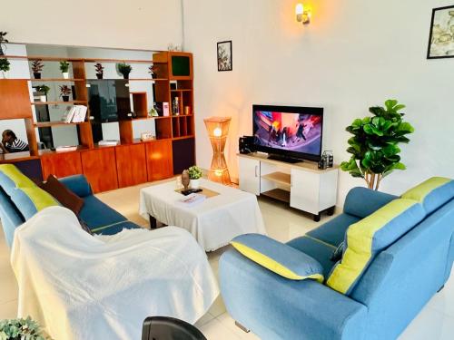 a living room with two blue chairs and a tv at Laksamana Homestay in Batu Pahat