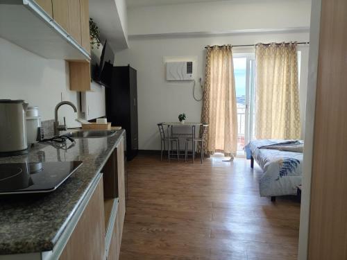 a kitchen and living room with a bed and a table at Cozy condo unit at Amani Grand near Cebu Airport in Pusok