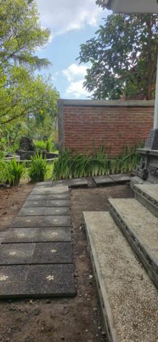 a walkway with a bench and a brick wall at Uma Nirmala Aling-Aling in Singaraja