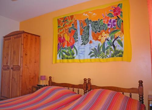 a bedroom with a painting of flowers on the wall at Les Hibiscus de la Rivière in Saint-Louis