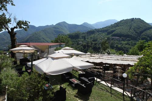 eine Gruppe von Sonnenschirmen und Tischen mit Bergen im Hintergrund in der Unterkunft Agriturismo da Regina in Tramonti