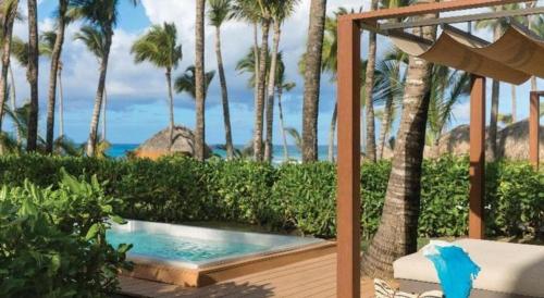 a swimming pool next to a deck with palm trees at EXCELLENCE PUNTA CANA - ALL INCLUSIVE - ADULTS ONLY in Punta Cana