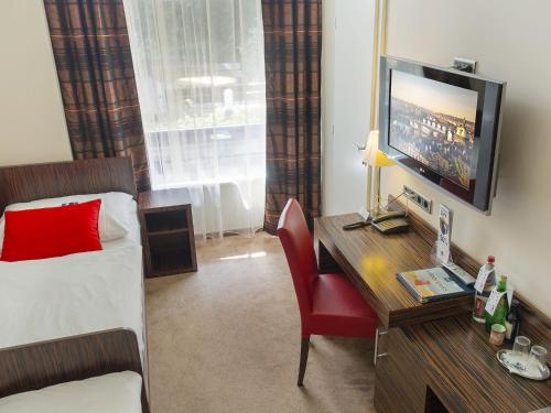 a hotel room with a bed and a desk with a television at EA Hotel Crystal Palace in Prague