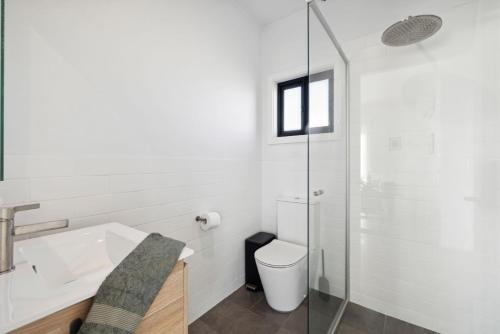 a white bathroom with a toilet and a sink at The Crystal Palace 2 in Jindabyne