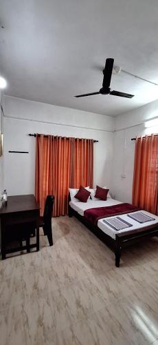 a bedroom with a bed and a desk in it at Holiday Apartments & Homestay in Sultan Bathery