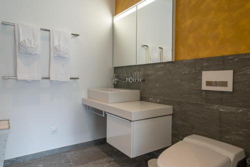 a bathroom with a sink and a toilet and a mirror at Edelweiss Mountain Suites 04-01 in Flims