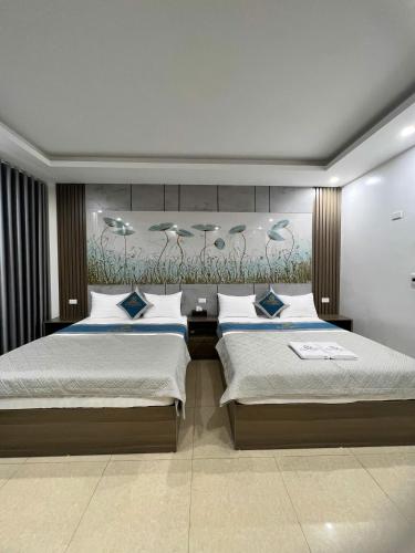 a bedroom with two beds and a painting on the wall at Ruby 3 Hotel in Hanoi