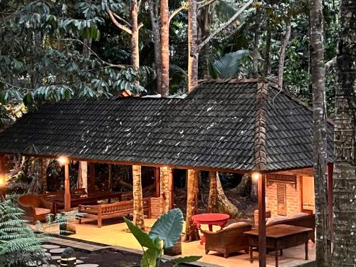 a wooden pavilion with a roof in a forest at The Manikyang Residence in Tabanan