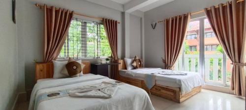 a bedroom with two beds and a large window at Sok San Boutique and Spa in Siem Reap