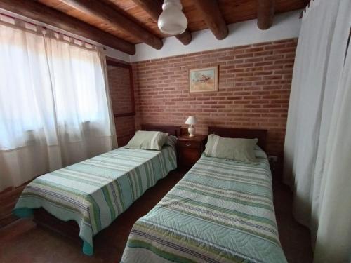 two beds in a room with a brick wall at Casa familiar de Campo Arev in Las Rabonas