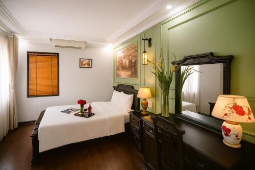 a bedroom with a white bed and a lamp at Sena Boutique Hotel & Travel in Hanoi
