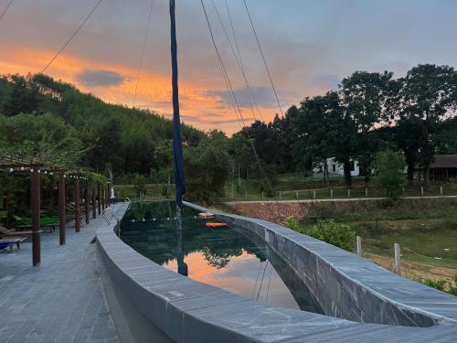 una barca è ormeggiata su un fiume al tramonto di Nguyen Shack Retreat Resort a Phong Nha