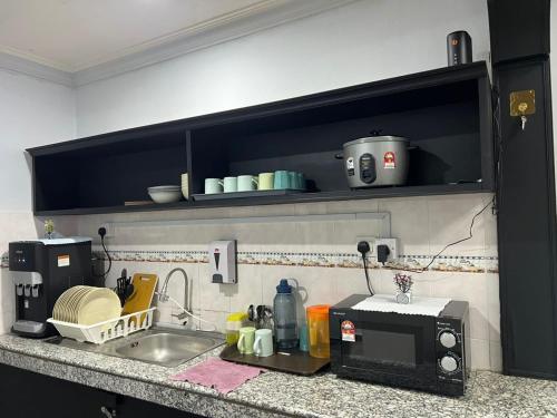 a kitchen counter with a sink and a microwave at Eiffel Villa Homestay in Simpang Empat