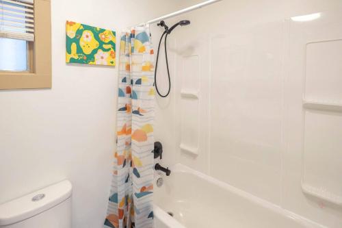 a bathroom with a shower curtain and a toilet at Retro Glam in Ramsay Walk to Stampede Grounds in Calgary