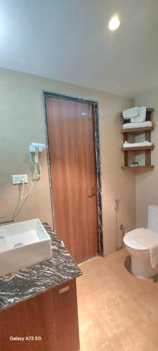 a bathroom with a toilet and a wooden door at Royal Tiger Luxury Resort in Sauraha