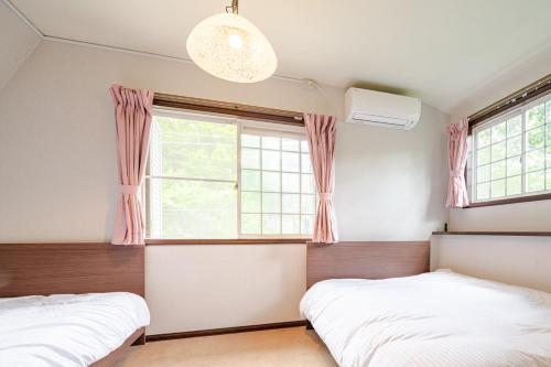 two beds in a bedroom with a window at 富士見テラス山中湖マイペンライ in Yamanakako
