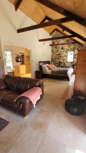 a living room with a leather couch and a stone wall at Adventure Bay Retreat Bruny Island in Adventure Bay
