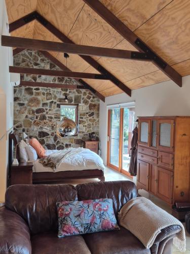 a living room with a bed and a leather couch at Adventure Bay Retreat Bruny Island in Adventure Bay