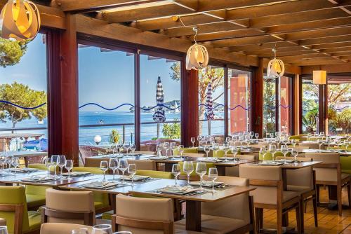a restaurant with tables and chairs and windows at Hôtel Vacances Bleues Delcloy in Saint-Jean-Cap-Ferrat