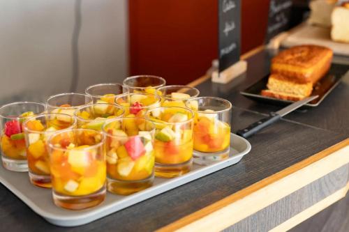 Una bandeja de vasos llenos de fruta en un mostrador. en Hôtel La Petite Auberge, en Chambretaud