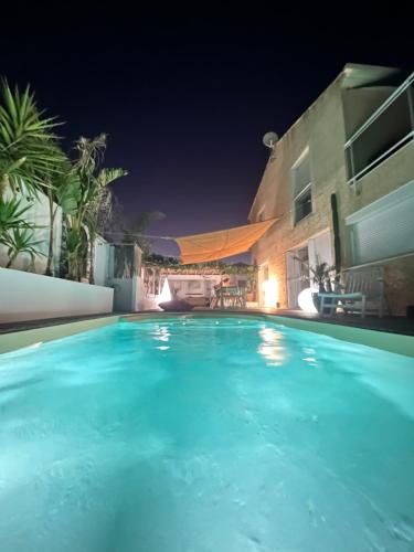 - une piscine avec une maison la nuit dans l'établissement Villa Les Dunes, à Frontignan