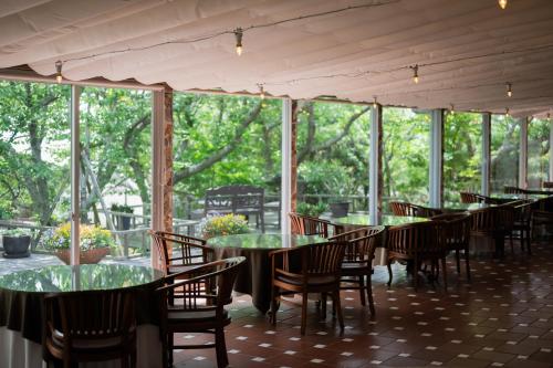 a dining room with tables and chairs and windows at Resort Hotel Moana Coast in Naruto