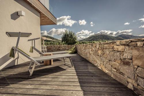 a stone wall with a bench on a wooden walkway at MALAT Weingut und Hotel in Furth