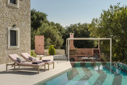 a swimming pool with two lounge chairs next to a house at Majestic Stone Villa Sea View Pool in Andipáta Erísou